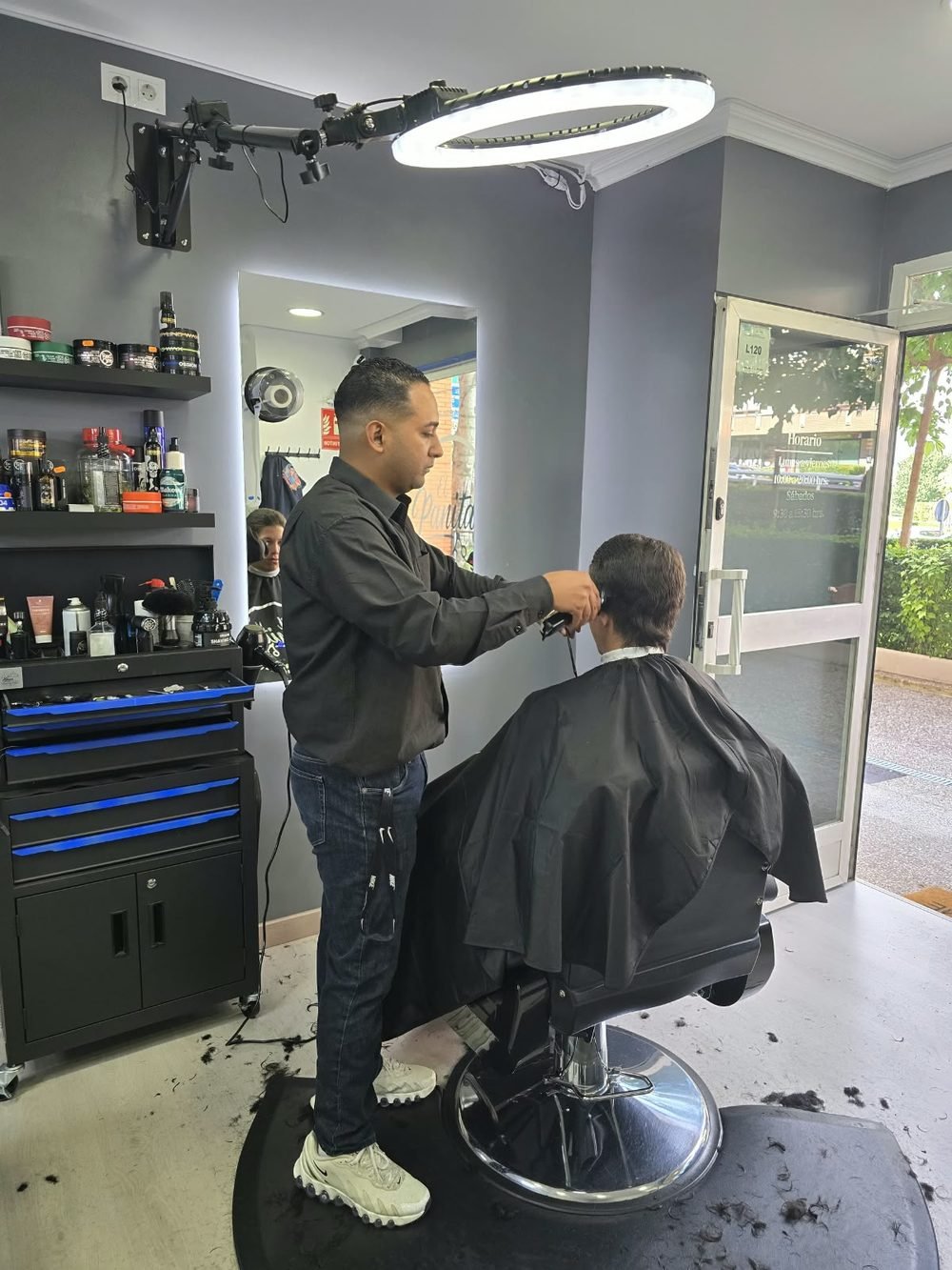 Barbero de El Panita apurando un corte junto al escaparate
